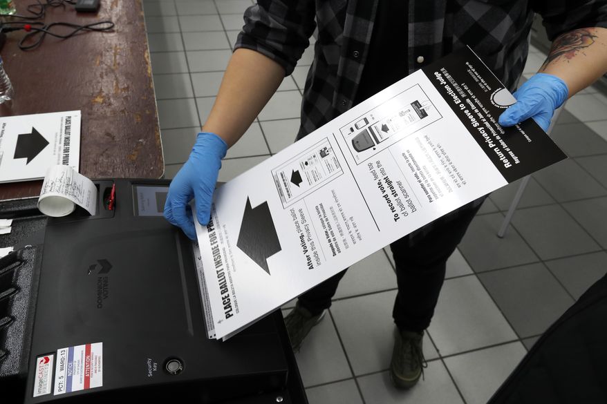In this March 17, 2020, file photo a poll worker at the Su Nueva Lavanderia polling place uses rubber gloves as she enters a ballot in the ballot box in Chicago. A new poll from The Associated Press-NORC Center for Public Affairs Research finds Democrats are now much more likely than Republicans to support their state conducting elections exclusively by mail, 47% to 29%. (AP Photo/Charles Rex Arbogast, File)