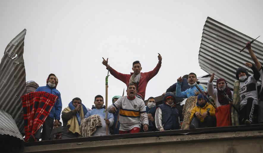 Rioting inmates protest from the roof of the Villa Devoto prison as they protest against authorities who they say are not doing enough to prevent the spread of coronavirus inside the jail in Buenos Aires, Argentina, Friday, April 24, 2020. (AP Photo/Natacha Pisarenko)