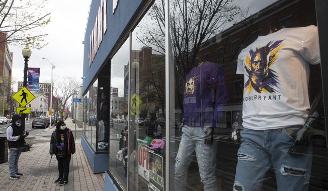 A couple of residents wearing face masks to protect from the coronavirus window shop at a closed clothing store on Main Street in downtown in Bridgeport, Conn, Monday, April 27, 2020. (AP Photo/Mary Altaffer)