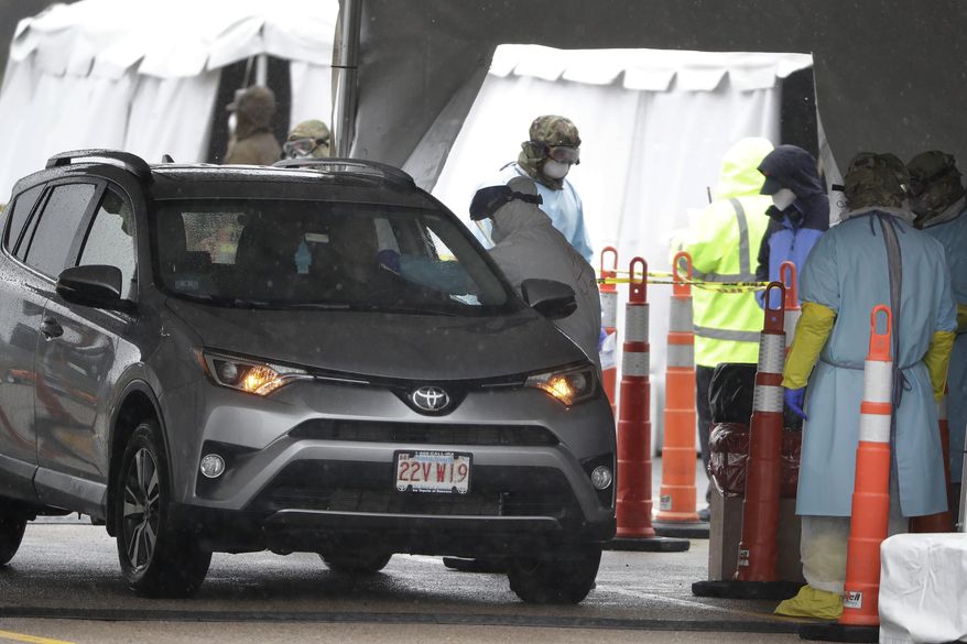 A medical worker, center, uses a swab to administer a test for the coronavirus to an unidentified person at a drive-thru testing site in a parking at Gillette Stadium, Monday, April 27, 2020, in Foxborough, Mass. The site is designated specifically for police officers, firefighters and other first responders who may have been exposed or are showing virus symptoms. (AP Photo/Steven Senne)