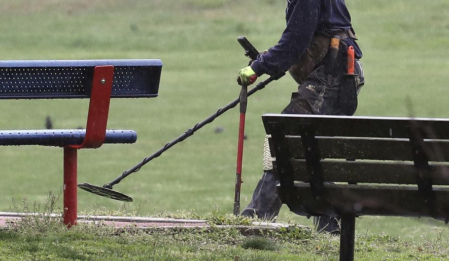 A treasure hunter scans the ground with his metal detector in an empty Kirby Park in Wilkes-Barre Pa., Sunday, April 26, 2020, during the coronavirus outbreak. (Dave Scherbenco/The Citizens' Voice via AP)