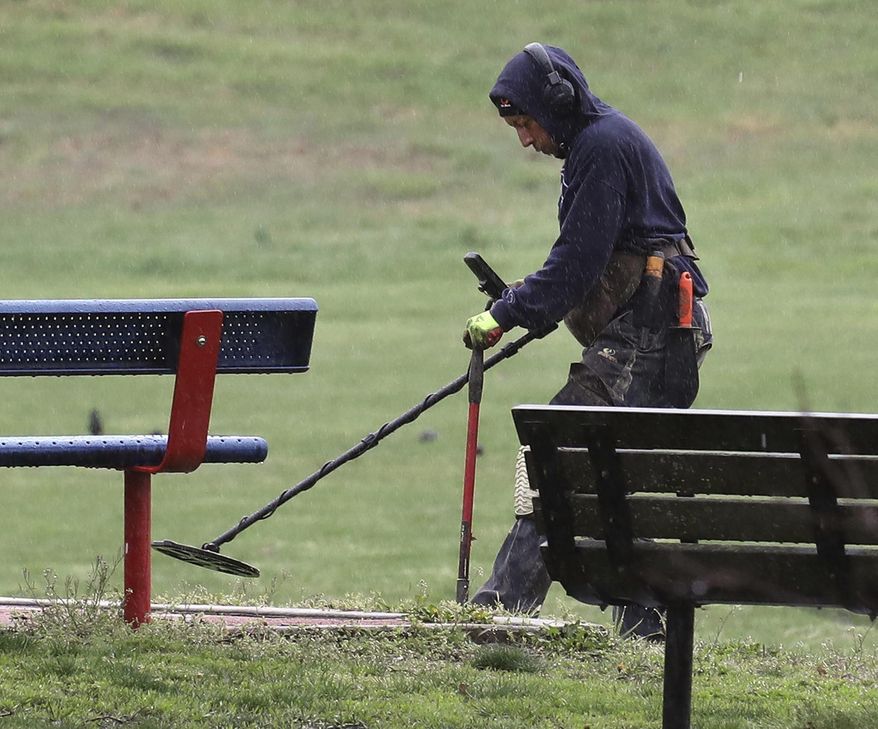 A treasure hunter scans the ground with his metal detector in an empty Kirby Park in Wilkes-Barre Pa., Sunday, April 26, 2020, during the coronavirus outbreak. (Dave Scherbenco/The Citizens' Voice via AP)