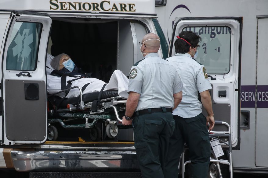 A patient is loaded into the back of an ambulance by medical personnel amid the coronavirus pandemic, Tuesday, April 28, 2020, outside NYU Langone Medical Center in New York. (AP Photo/John Minchillo)