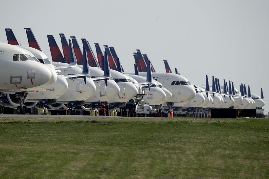 FILE - In this April 1, 2020, file photo, several dozen mothballed Delta Air Lines jets are parked at Kansas City International Airport in Kansas City, Mo.  Investors are now getting their first look at companies navigating the coronavirus pandemic. A clearer snapshot of the business landscape should start to formulate by keeping an eye on the busiest week of the earnings season as many companies are reporting earnings on Tuesday, April 28. (AP Photo/Charlie Riedel, File)