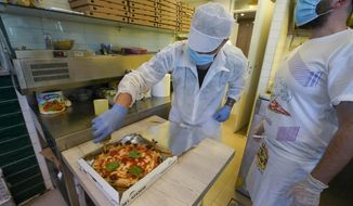 Olive oil is put on a pizza ready to be home delivered, at the Caputo pizzeria in Naples, Italy, Monday, April 27, 2020. Region Campania allowed cafes and pizzerias to reopen for delivery Monday, after a long precautionary closure due to the coronavirus outbreak. (AP Photo/Andrew Medichini)