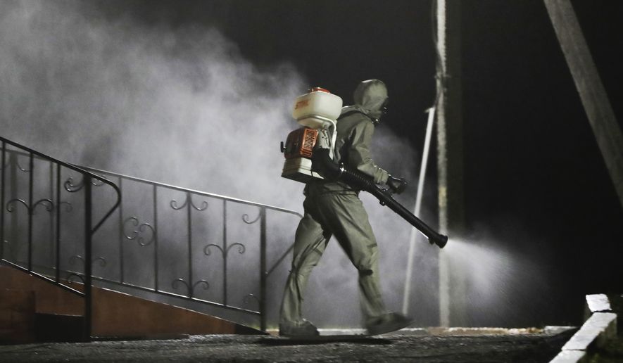A serviceman of Belarus Ministry of Defence wearing protective gear disinfects a local hospital in the town of Zaslavl, outside the capital Minsk, Belarus, Wednesday, April 29, 2020. The World Health Organization is urging the government of Belarus to cancel public events and implement measures to ensure physical and social distancing amid the growing coronavirus outbreak. (AP Photo/Sergei Grits)