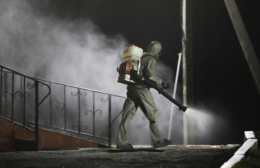 A serviceman of Belarus Ministry of Defence wearing protective gear disinfects a local hospital in the town of Zaslavl, outside the capital Minsk, Belarus, Wednesday, April 29, 2020. The World Health Organization is urging the government of Belarus to cancel public events and implement measures to ensure physical and social distancing amid the growing coronavirus outbreak. (AP Photo/Sergei Grits)