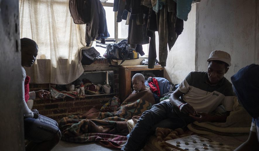 Bakair Zaina, a blind migrant from Mozambique, sits on the floor of his room he shares with two sons in Johannesburg, South Africa on April 14, 2020. A total of 23 families of blind and disabled foreign nationals living in the dilapidated building and earning a living by street begging have been hard hit by South Africa's lockdown as they are forced to remain indoors. (AP Photo/Bram Janssen)