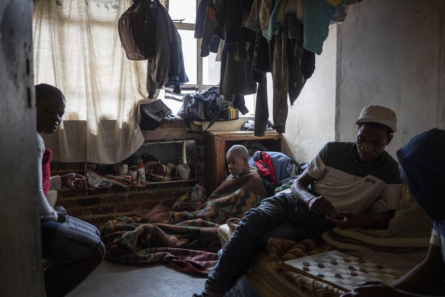 Bakair Zaina, a blind migrant from Mozambique, sits on the floor of his room he shares with two sons in Johannesburg, South Africa on April 14, 2020. A total of 23 families of blind and disabled foreign nationals living in the dilapidated building and earning a living by street begging have been hard hit by South Africa's lockdown as they are forced to remain indoors. (AP Photo/Bram Janssen)