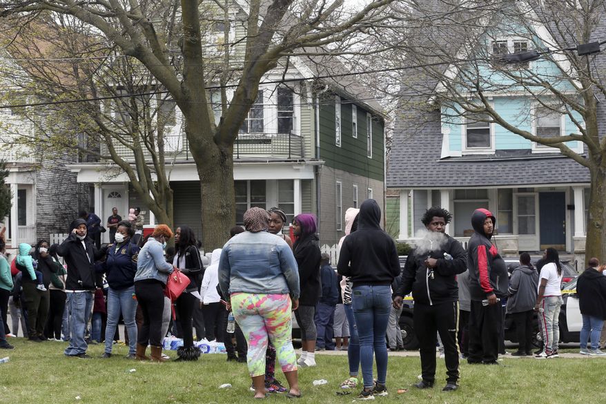 A crowd gathers at the scene of a shooting where five people were killed in Milwaukee, Wis., Monday, April 27, 2020. Police Chief Alfonso Morales said his department received a call around 10:30 a.m. Monday from a man who said his family was dead. The man who called authorities to the house has been taken into custody, and detectives were trying to determine the relationship between the caller and the victims, Morales said. No names have been provided. (Angela Peterson/Milwaukee Journal-Sentinel via AP)