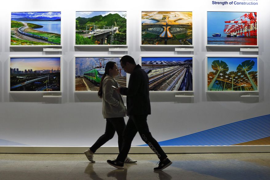 People walk by a display board showcasing China's sweeping infrastructure-building projects at the media center of the Belt and Road Forum in Beijing. African leaders in 2020 are asking what China can do for them as the coronavirus pandemic threatens to destroy economies across a continent where Beijing is both the top trading partner and top lender. (AP Photo/Andy Wong, File)
