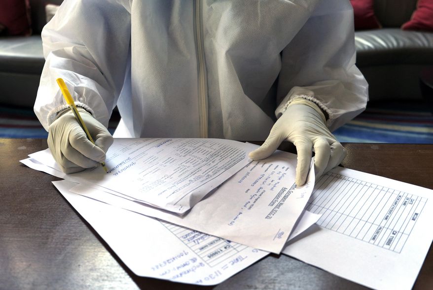 In this April 24, 2020, photo, a doctor fills a form for the second swab test of Associated Press photographer Rafiq Maqbool at a hotel room where the photographer is in quarantine, in Mumbai, India. Maqbool was tested positive for COVID-19 with dozens of other journalists, who were then moved collectively to a hotel turned quarantine center. He left his wife and children home alone to deal with a sealed building, anxious relatives and the stigma of being related to someone who had caught the virus. On the seventh day, the test from his second swab test turned out negative and he was allowed to return home to be under home quarantine for 14 days. (AP Photo/Rafiq Maqbool)
