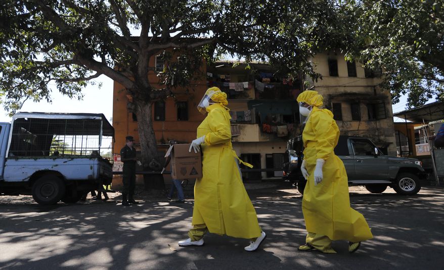 Sri Lankan health officials arrive to collect swab specimen from the suspected COVID-19 cases in a residential neighborhood during lockdown in Colombo, Sri Lanka, Thursday, April 16, 2020. Sri Lankan authorities claim they have largely managed to prevent community spreading through proper identification and isolation of people who came into contact with COVID-19 patients. (AP Photo/Eranga Jayawardena)