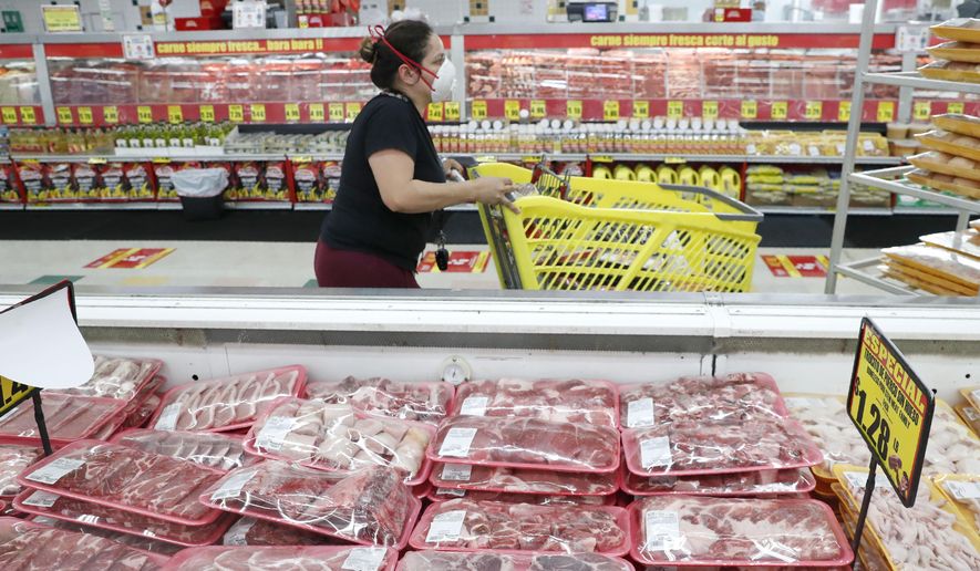 Amid concerns of the spread of COVID-19, a shopper wears a mask as she walks through the meat products at a grocery store in Dallas, Wednesday, April 29, 2020. (AP Photo/LM Otero)