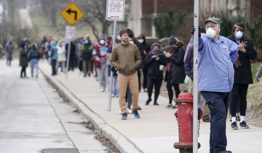 FILE - In this April 7, 2020 file photo, voters observe social distancing guidelines as they wait in line to cast ballots in the presidential primary election in Milwaukee. More than 50 people who voted in person or worked the polls during Wisconsin's election earlier this month have tested positive for COVID-19 so far. But there are no plans to move or otherwise alter a special congressional election coming in less than two weeks. (AP Photo/Morry Gash File)