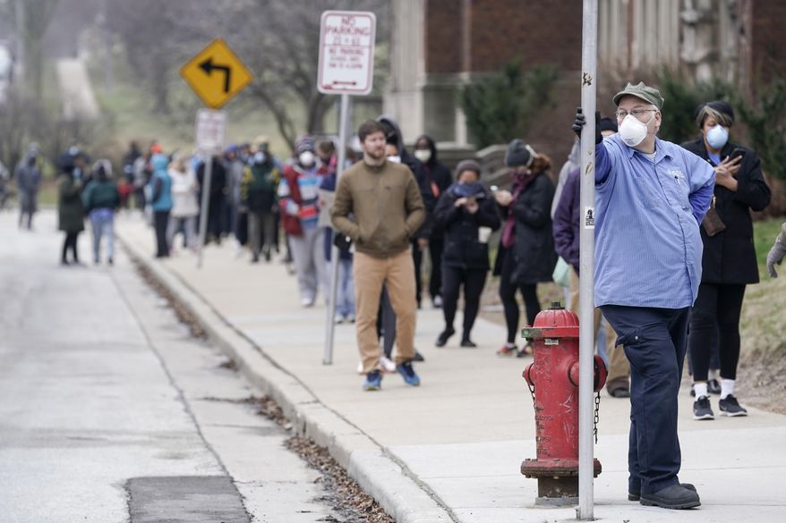 FILE - In this April 7, 2020 file photo, voters observe social distancing guidelines as they wait in line to cast ballots in the presidential primary election in Milwaukee. More than 50 people who voted in person or worked the polls during Wisconsin's election earlier this month have tested positive for COVID-19 so far. But there are no plans to move or otherwise alter a special congressional election coming in less than two weeks. (AP Photo/Morry Gash File)