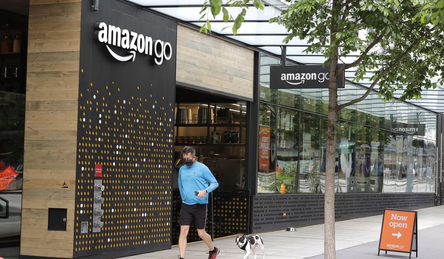 A person wearing a mask jogs past an Amazon Go store, Thursday, April 30, 2020, in downtown Seattle. Amazon.com is expected to announce earnings for the first quarter of 2020 at the close of markets Thursday, a report that is expected to be closely watched due to the effects of the coronavirus outbreak on the company. (AP Photo/Ted S. Warren)