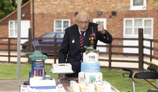In this photo provided by Capture the Light Photography,  Second World War veteran Captain Tom Moore poses with birthday cakes as he celebrates his 100th birthday, in Bedford, England, Thursday April 30, 2020. A British army veteran who started walking laps in his garden as part of a humble fundraiser for the National Health Service is celebrating his 100th birthday after warming the hearts of a nation that donated millions of pounds to back his appeal. (Emma Sohl/Capture the Light Photography via AP)
