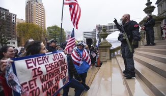Members of the Michigan Liberty Militia, including Phil Robinson, right, join protesters at a rally at the state Capitol in Lansing, Mich., Thursday, April 30, 2020. Hoisting American flags and handmade signs, protesters returned to the state Capitol to denounce Gov. Gretchen Whitmer&#x27;s stay-home order and business restrictions due to COVID-19, while lawmakers met to consider extending her emergency declaration hours before it expires. (Matthew Dae Smith/Lansing State Journal via AP)