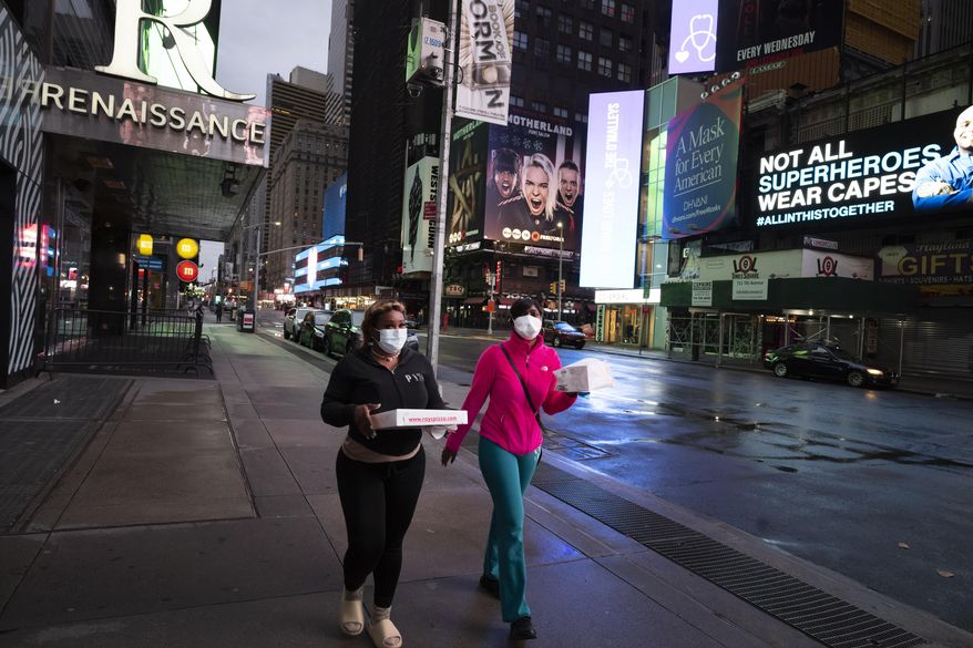 People carry takeout food in New York&#39;s Times Square, Wednesday night, April 29, 2020, during the coronavirus pandemic. President Donald Trump said Wednesday the federal government will not be extending its coronavirus social distancing guidelines once they expire Thursday. (AP Photo/Mark Lennihan)