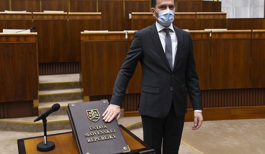 FILE - In this Friday, March 20, 2020 file photo, Designated Slovakian Prime Minister Igor Matovic wearing a face mask takes the oath during the inaugural session of the new Parliament, in Bratislava, Slovakia. Slovakia’s president has sworn in a new government led by the winning party in the parliamentary election. President Zuzana Caputova appointed a four-party coalition led by Igor Matovic whose center-right populist opposition group Ordinary People captured 25% of the Feb. 29 vote. All present at the ceremony on Saturday, March 21, 2020 had protective face masks and gloves amid the outbreak of the coronavirus. (Michal Svitok/TASR via AP, File)