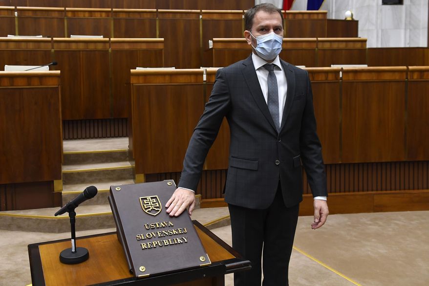 FILE - In this Friday, March 20, 2020 file photo, Designated Slovakian Prime Minister Igor Matovic wearing a face mask takes the oath during the inaugural session of the new Parliament, in Bratislava, Slovakia. Slovakia’s president has sworn in a new government led by the winning party in the parliamentary election. President Zuzana Caputova appointed a four-party coalition led by Igor Matovic whose center-right populist opposition group Ordinary People captured 25% of the Feb. 29 vote. All present at the ceremony on Saturday, March 21, 2020 had protective face masks and gloves amid the outbreak of the coronavirus. (Michal Svitok/TASR via AP, File)