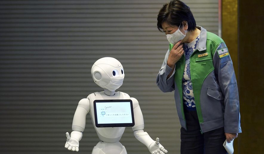 A humanoid robot Pepper wearing a face mask greets Tokyo Gov. Yuriko Koike at the lobby of a hotel for the new coronavirus COVID-19 patients with mild symptoms during a media preview in Tokyo Friday, May 1, 2020. Prime Minister Shinzo Abe said Thursday he planned to extend a state of emergency beyond the scheduled end of May 6 because infections are spreading and hospitals are overburdened. (AP Photo/Eugene Hoshiko)