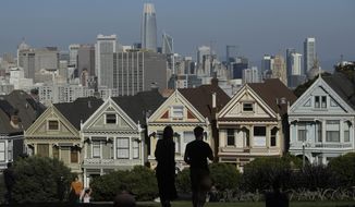 In this Feb. 26, 2020, file photo, visitors look toward the &quot;Painted Ladies,&quot; a row of historical Victorian homes, in front of the San Francisco skyline from Alamo Square Park in San Francisco. An estimate released Friday, May 1, 2020, by the California Department of Finance said that more people are leaving California than moving in, evidence of the toll the state&#x27;s housing crisis is taking as the world&#x27;s fifth largest economy inches toward 40 million people. (AP Photo/Jeff Chiu, File)