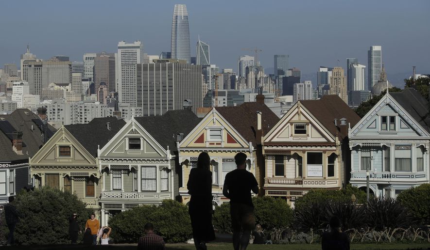 In this Feb. 26, 2020, file photo, visitors look toward the &quot;Painted Ladies,&quot; a row of historical Victorian homes, in front of the San Francisco skyline from Alamo Square Park in San Francisco. An estimate released Friday, May 1, 2020, by the California Department of Finance said that more people are leaving California than moving in, evidence of the toll the state&#39;s housing crisis is taking as the world&#39;s fifth largest economy inches toward 40 million people. (AP Photo/Jeff Chiu, File)
