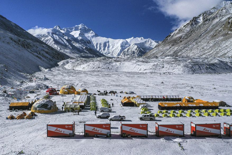 In this April 30, 2020, aerial photo released by China's Xinhua News Agency, vehicles and tents are seen at the base camp at the foot of the peak of Mount Qomolangma, also known as Mount Everest, in southwestern China's Tibet Autonomous Region. China sent scientists to climb Mount Everest while the world's highest peak is empty of commercial climbers because of the coronavirus pandemic. (Purbu Zhaxi/Xinhua via AP)