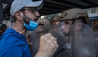 Army soldiers face off with an anti-government protester during May Day protests near the Lebanese Central Bank in Beirut, Lebanon, Friday, May 1, 2020. Hundreds rallied outside the country&#39;s central bank and in other parts of the country a day after the prime minister said he&#39;ll be seeking a rescue program from the International Monetary Fund to deal with a spiraling economic crisis. (AP Photo/Hassan Ammar)