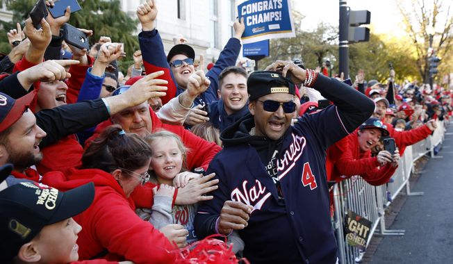 FILE - In this Nov. 2, 2019, file photo, Washington Nationals manager Dave Martinez celebrates with fans during a parade to celebrate the team&#x27;s World Series baseball championship over the Houston Astros in Washington. Martinez says the World Series champs will raise their banner and present their rings at their stadium with fans in attendance -- no matter how or when or if the 2020 season starts. Like his general manager, Mike Rizzo, Martinez is optimistic there will be a major league season this year and has been mapping out what a second spring training camp might look like. (AP Photo/Patrick Semansky, File)