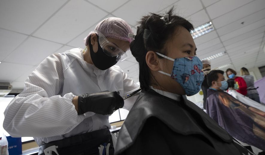 In this Tuesday, April 28, 2020, photo, Pornsupa Hattayong gives haircuts to a medical worker treating COVID-19 patients at Bangkok Metropolitan Administration General Hospital in Bangkok, Thailand. The 43-year-old hairstylist is boosting the morale of frontline medical workers by dispensing free haircuts at Bangkok hospitals since Thailand’s hair salons have been closed for more than a month, to help stop the spread of the coronavirus. (AP Photo/Sakchai Lalit)