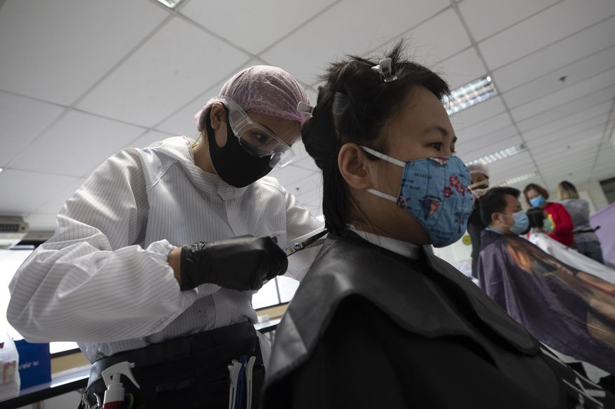 In this Tuesday, April 28, 2020, photo, Pornsupa Hattayong gives haircuts to a medical worker treating COVID-19 patients at Bangkok Metropolitan Administration General Hospital in Bangkok, Thailand. The 43-year-old hairstylist is boosting the morale of frontline medical workers by dispensing free haircuts at Bangkok hospitals since Thailand’s hair salons have been closed for more than a month, to help stop the spread of the coronavirus. (AP Photo/Sakchai Lalit)
