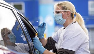 A person is tested for coronavirus at the drive-through facility at the Edgbaston Cricket Ground Covid-19 testing site in Birmingham, England, Saturday, May 2, 2020. (Jacob King/PA via AP)