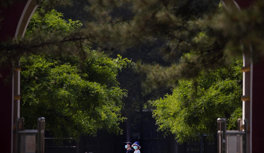 People wear face masks to protect against the new coronavirus as they walk through a public park in Beijing, Saturday, May 2, 2020. China, where the pandemic began in December, reported one new infection and no deaths in the 24 hours through midnight Friday. (AP Photo/Mark Schiefelbein)
