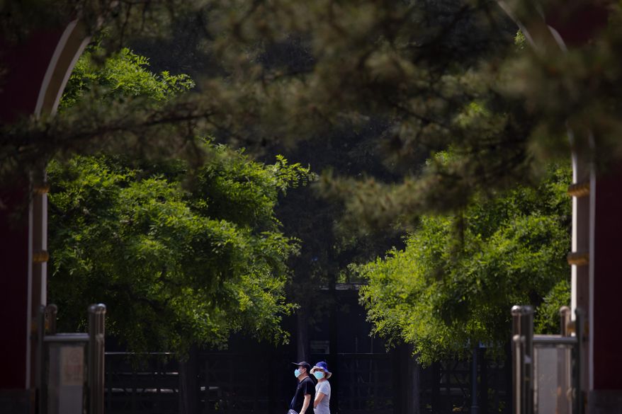 People wear face masks to protect against the new coronavirus as they walk through a public park in Beijing, Saturday, May 2, 2020. China, where the pandemic began in December, reported one new infection and no deaths in the 24 hours through midnight Friday. (AP Photo/Mark Schiefelbein)