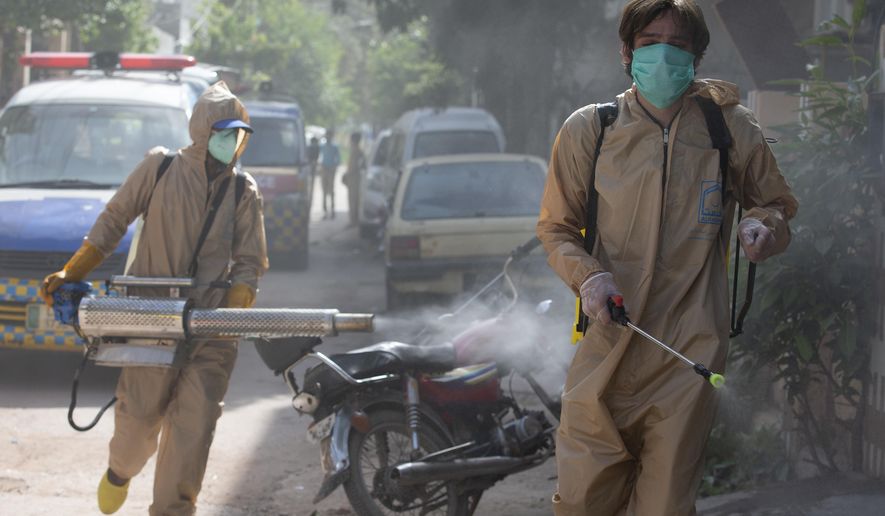 Volunteers disinfect the area which authorities sealed off after a group of people tested positive for the coronavirus, Friday, May 1, 2020. The government imposed a nationwide lockdown to try to contain the outbreak of the virus. (AP Photo/B.K. Bangash)
