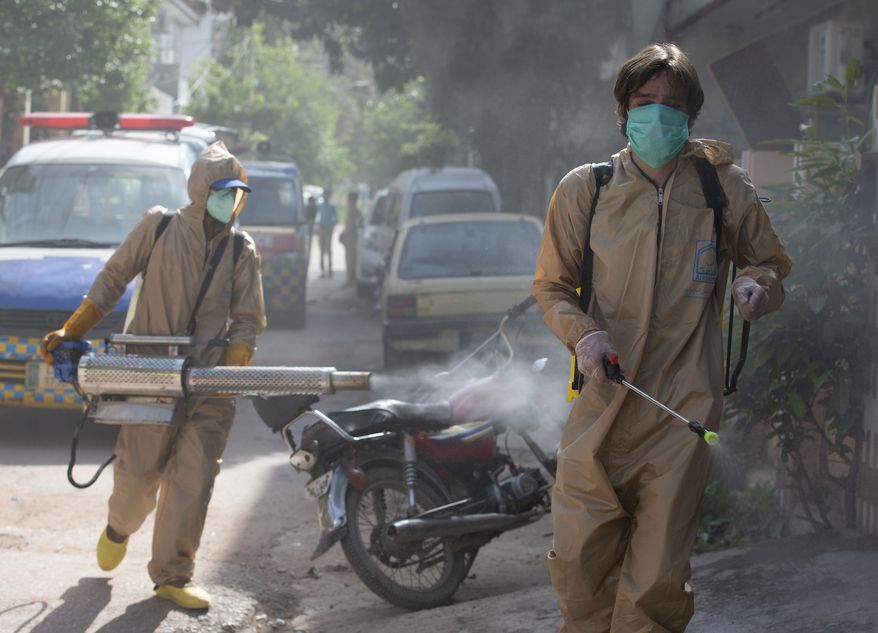 Volunteers disinfect the area which authorities sealed off after a group of people tested positive for the coronavirus, Friday, May 1, 2020. The government imposed a nationwide lockdown to try to contain the outbreak of the virus. (AP Photo/B.K. Bangash)