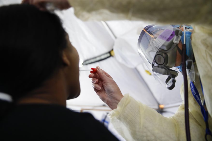 FILE - In this April 20, 2020, photo, a test is performed on a patient in a COVID-19 triage tent at St. Joseph's Hospital in Yonkers, N.Y. An Associated Press analysis finds that most states are not meeting the minimum levels of testing suggested by the federal government and recommended by public health researchers even as many of them begin to reopen their shattered economies. (AP Photo/John Minchillo)