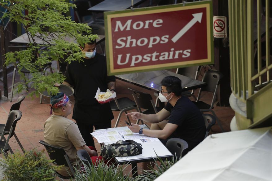 A waiter serves a group dinning at a restaurant that reopen at the River Walk in San Antonio, Friday, May 1, 2020. Texas' stay-at-home orders due to the COVID-19 pandemic have expired and Texas Gov. Greg Abbott has eased restrictions on many businesses that have now opened. (AP Photo/Eric Gay)