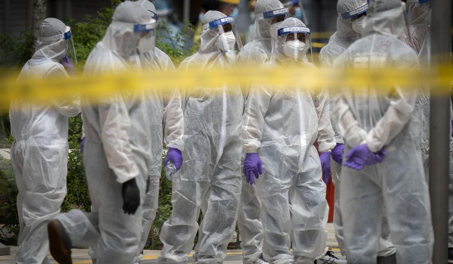 Immigration officers wearing full protection suits prepare at a coronavirus locked down area in Kuala Lumpur, Malaysia, on Sunday, May 3, 2020. Malaysian Prime Minister Muhyiddin Yassin says the economy needs to be revived as billions have been lost during the partial lockdown that began in March. (AP Photo/Vincent Thian)