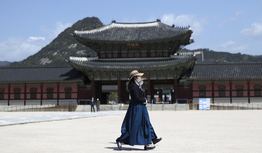 FILE - In this April 23, 2020 file photo, women wearing masks as a precaution against the new coronavirus, walk at the Gyeongbok Palace, in Seoul, South Korea. Nervous travelers, spotty air service, health risks _ the battered global tourism industry is facing unprecedented uncertainty in the wake of the new coronavirus. Millions of workers are laid off or furloughed, and it will likely take years for the industry to get back to the strong demand it was seeing just six months ago. (AP Photo/Lee Jin-man, File)