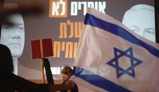 A man wearing a mask for protection against the spread of the coronavirus holds a sign in front of a poster of Israeli Prime Minister Benjamin Netanyahu, right, and Benny Gantz, left, that reads: &amp;quot;say no the a corrupt government, &amp;quot; as another one holds and Israeli flag during a protest against the government and the corruption, at Rabin square in Tel Aviv, Israel, Saturday, May 2, 2020. Several thousand Israelis took to the streets on Saturday night, demonstrating against Prime Minister Benjamin Netanyahu&#39;s new coalition deal with his chief rival a day before the country&#39;s Supreme Court is to begin debating a series of legal challenges to the agreement.(AP Photo/Ariel Schalit)