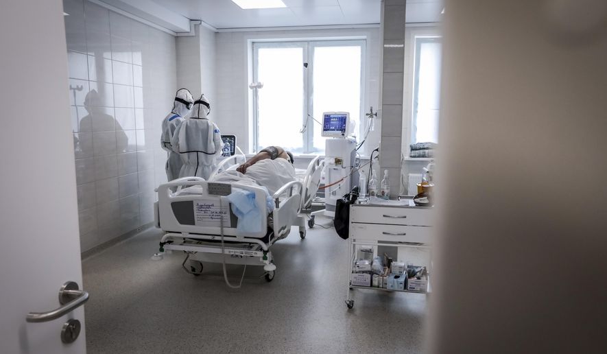 In this photo taken on Saturday, May 2, 2020, doctors attend a patient inside the intensive care unit for people infected with the new coronavirus, at a hospital in Moscow, Russia, Saturday, May 2, 2020. A Russian epidemiologist says the sharp increase in coronavirus infection cases recorded over the past week reflects increased testing. Russia on Sunday reported more then ten thousand new cases, nearly double the new cases reported a week ago and the first time the daily tally went into five digits.(AP Photo/Sophia Sandurskaya)