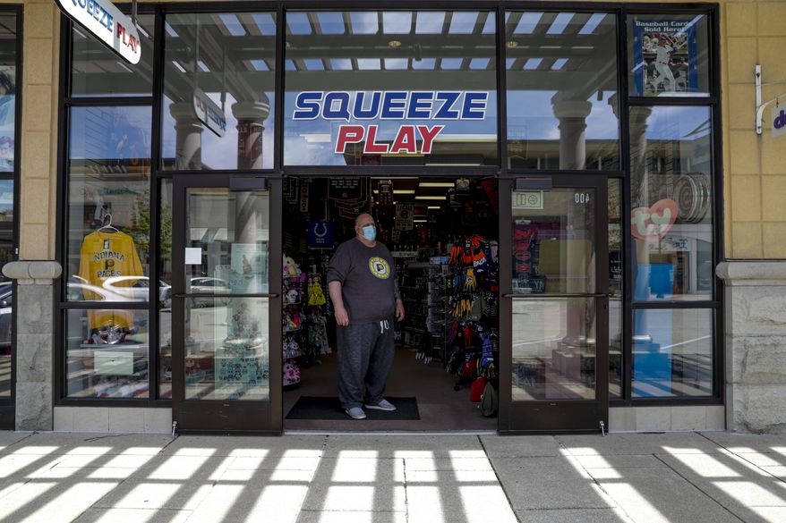 Tony Myers waits for customers in the doorway to Squeeze Play a team sports memorabilia and clothing store in the Hamilton Town Center in Noblesville, Ind., Monday, May 4, 2020. Indiana allowed real stores to open with capacity after restrictions put in place to curb the spread of the new coronavirus were rolled back. Less than 20 percent of the stores in the shopping center were open. (AP Photo/Michael Conroy)