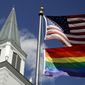 In this April 19, 2019, file photo, a gay pride rainbow flag flies along with the U.S. flag in front of the Asbury United Methodist Church in Prairie Village, Kan. (AP Photo/Charlie Riedel, File)