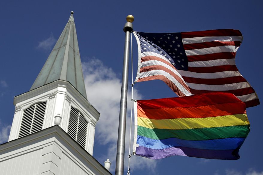 In this April 19, 2019, file photo, a gay pride rainbow flag flies along with the U.S. flag in front of the Asbury United Methodist Church in Prairie Village, Kan. (AP Photo/Charlie Riedel, File)
