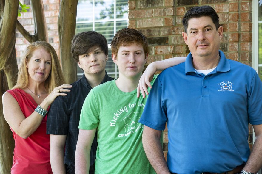 Jason Dyke, right, and his wife, April, left, pose for a portrait with their sons Ryan and Alex at their home in Coppell, Texas, Tuesday, April 21, 2020. Another son, Carson, died by suicide at age 11 three years ago, and the parents have since created Carson's Village — a nonprofit aiming to help families navigate the grief and loss of loved ones with resources and advice. The coronavirus pandemic has complicated that work, but it has also led to new ways to help families of COVID-19 victims or those who have died from other causes during this difficult time. (Lynda M. Gonzalez/The Dallas Morning News via AP)