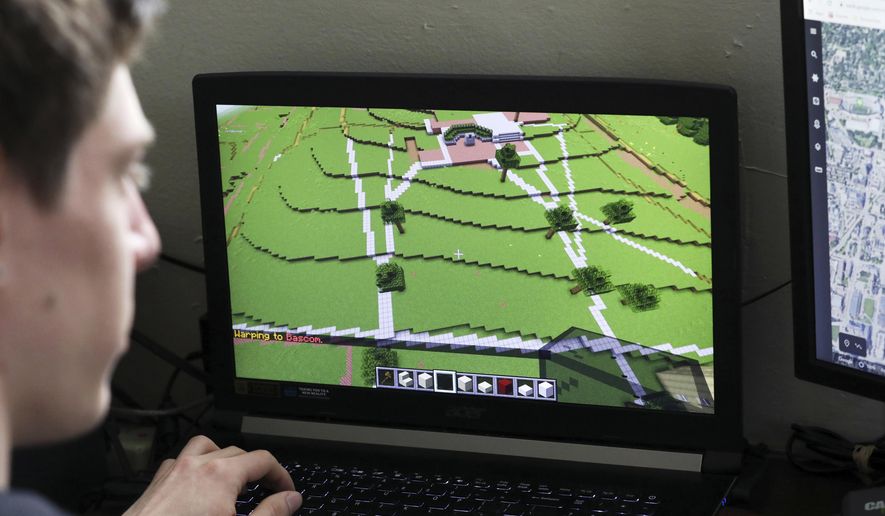 In this April 23, 2020, photo, UW-Madison graduate Zach Powers works on virtually building Bascom Hall in Minecraft at his apartment in Madison, Wis. Student organizations hold Zoom meetings and the Wisconsin Union created coloring pages. The Office of Sustainability moved the recent Earth Day celebrations online, including do-it-yourself crafts and yoga held over Facebook Live. An informal group of students and alumni are virtually creating the campus on Minecraft, a popular video game where users construct buildings and communities. On tap is a university-wide virtual festival for students to listen to a cappella groups, play Badger trivia and more. (Amber Arnold/Wisconsin State Journal via AP)